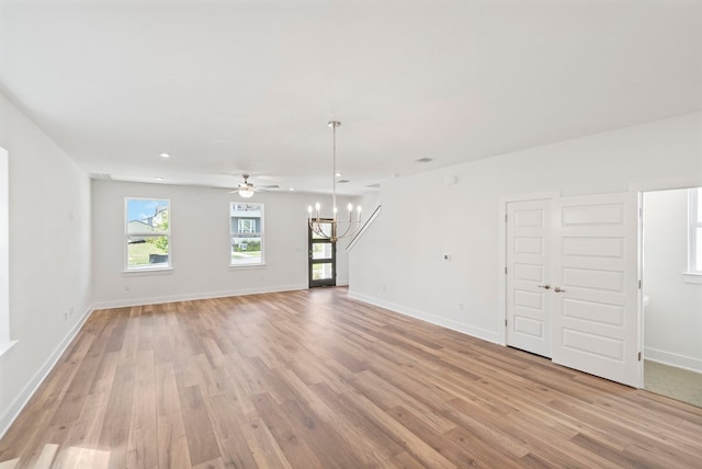 interior space with ceiling fan with notable chandelier and light hardwood / wood-style flooring