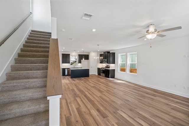 unfurnished living room featuring ceiling fan and hardwood / wood-style flooring