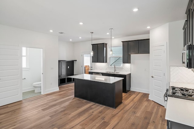 kitchen featuring dark wood-type flooring, a kitchen island, tasteful backsplash, and sink