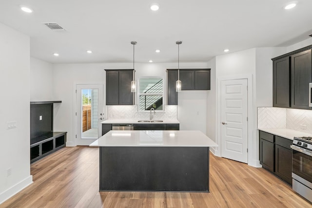 kitchen with light hardwood / wood-style flooring, stainless steel appliances, a kitchen island, sink, and decorative backsplash