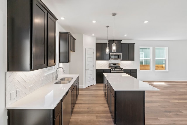 kitchen featuring appliances with stainless steel finishes, light hardwood / wood-style floors, sink, a kitchen island, and decorative backsplash