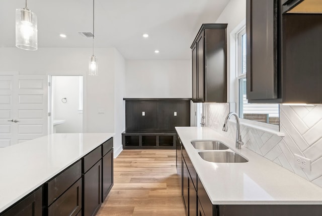 kitchen featuring sink, decorative light fixtures, backsplash, and light hardwood / wood-style floors