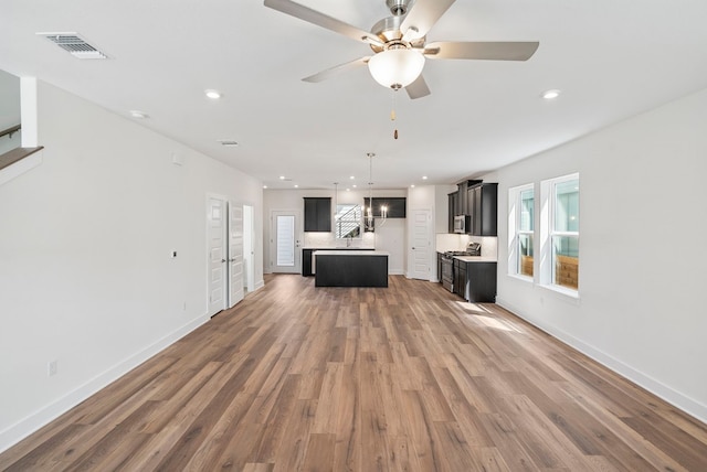 unfurnished living room featuring ceiling fan and hardwood / wood-style flooring