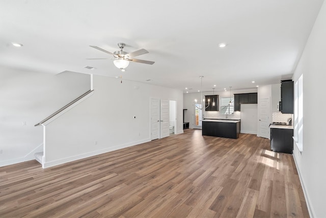 unfurnished living room with ceiling fan and wood-type flooring