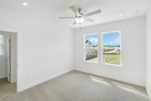 spare room with ceiling fan and light colored carpet