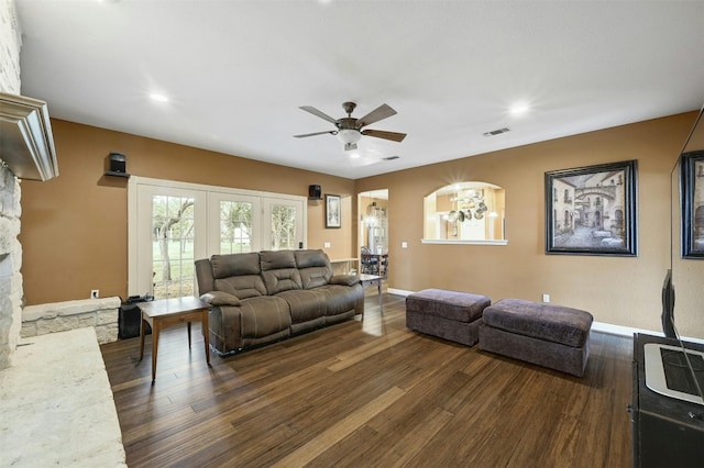 living room with dark hardwood / wood-style flooring and ceiling fan with notable chandelier