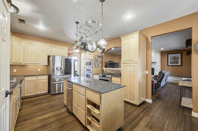 kitchen with stainless steel appliances, pendant lighting, a fireplace, dark hardwood / wood-style floors, and a kitchen island