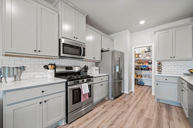 kitchen featuring light hardwood / wood-style flooring, appliances with stainless steel finishes, gray cabinets, and tasteful backsplash