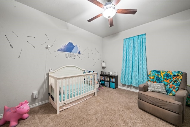 carpeted bedroom featuring ceiling fan and a nursery area