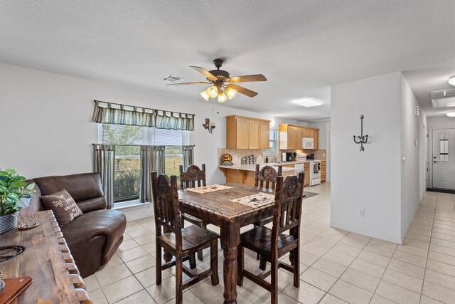 tiled dining space featuring ceiling fan and a textured ceiling