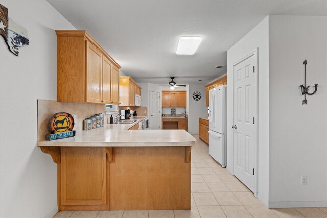 kitchen featuring white appliances, sink, a kitchen breakfast bar, kitchen peninsula, and ceiling fan