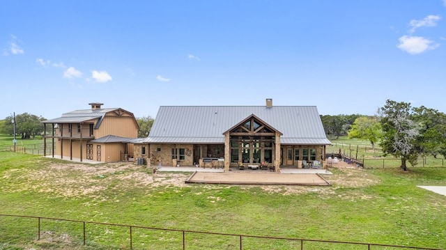 rear view of property with a rural view, a yard, and a patio