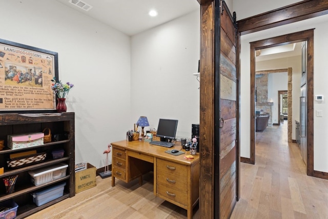 office space with a barn door and light hardwood / wood-style flooring