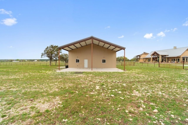 back of property featuring a lawn, a patio area, and a rural view