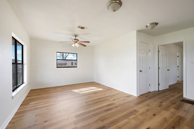 empty room with a healthy amount of sunlight, hardwood / wood-style floors, and ceiling fan