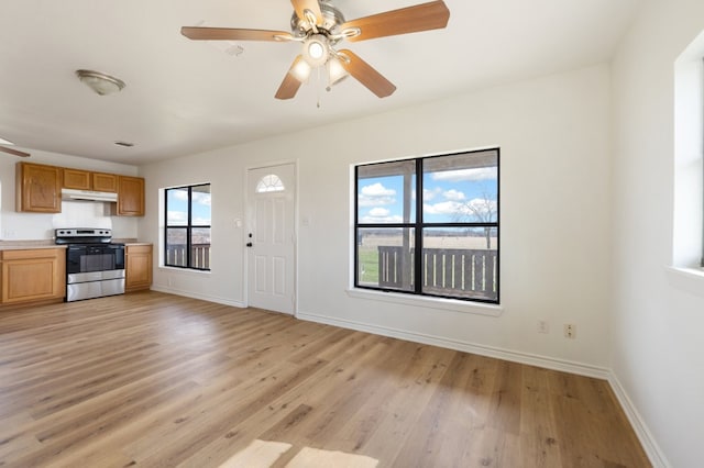 kitchen featuring ceiling fan, electric range, light wood-type flooring, and a wealth of natural light