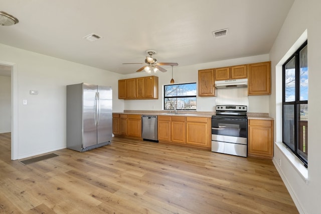 kitchen with light wood-type flooring, ceiling fan, sink, and stainless steel appliances