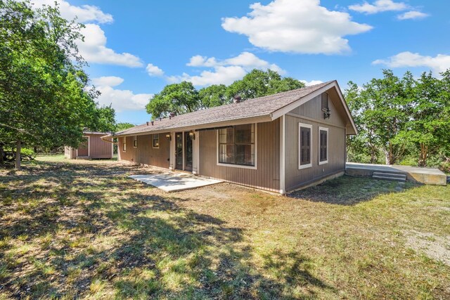 back of property with a lawn and a patio