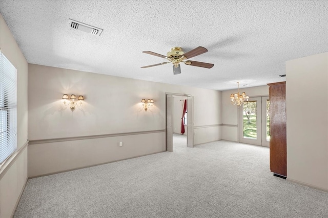 carpeted empty room with a textured ceiling and ceiling fan with notable chandelier