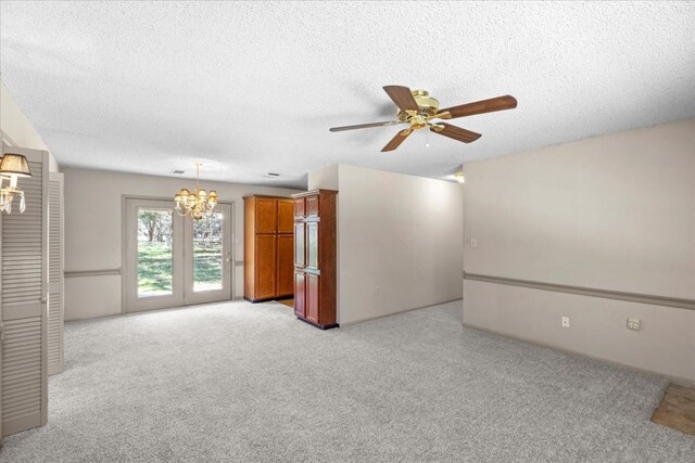 carpeted empty room featuring a textured ceiling and ceiling fan with notable chandelier