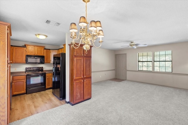 kitchen featuring light colored carpet, pendant lighting, black appliances, and ceiling fan with notable chandelier