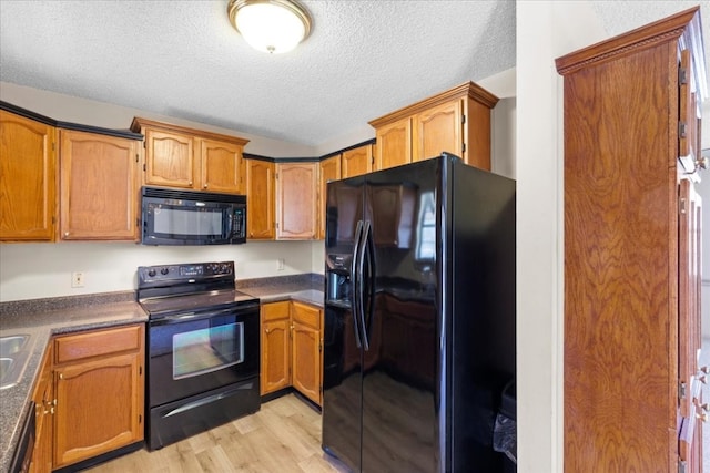 kitchen with a textured ceiling, light hardwood / wood-style floors, and black appliances