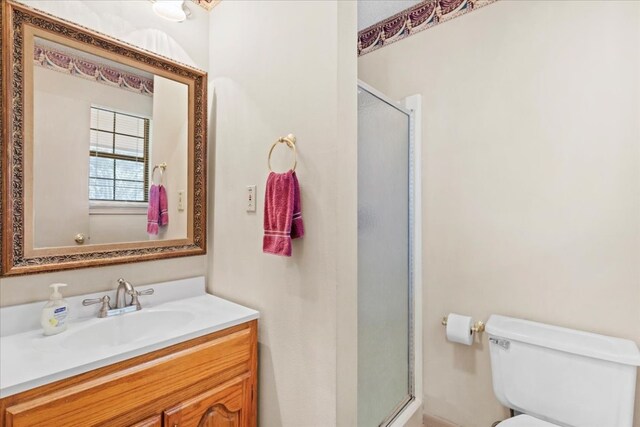 bathroom with toilet, a shower with door, and oversized vanity