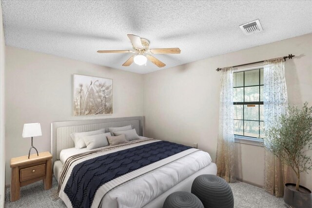 carpeted bedroom featuring ceiling fan and a textured ceiling