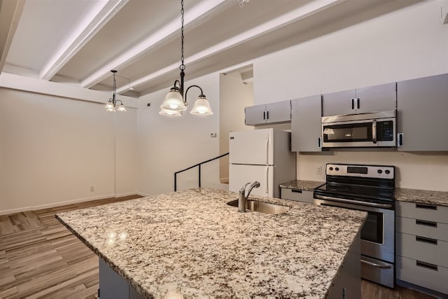 kitchen featuring appliances with stainless steel finishes, a chandelier, a kitchen island with sink, light stone countertops, and beam ceiling