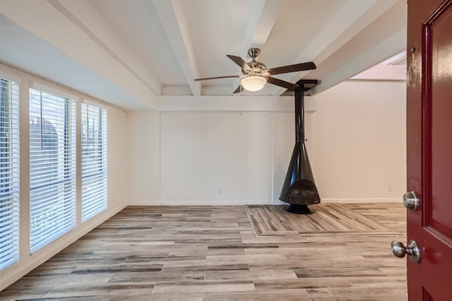 empty room featuring beam ceiling, light hardwood / wood-style floors, and ceiling fan