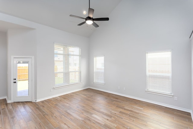 empty room with high vaulted ceiling, ceiling fan, and light hardwood / wood-style flooring