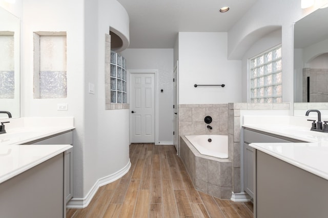 bathroom featuring hardwood / wood-style floors, tiled bath, and vanity