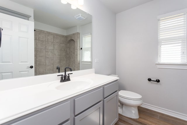 bathroom with large vanity, toilet, and wood-type flooring