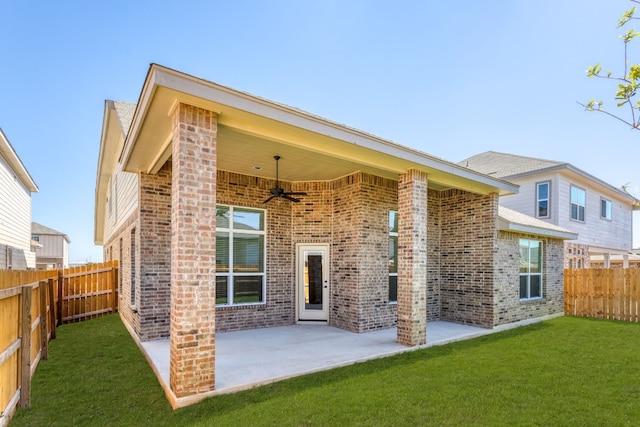 rear view of property featuring ceiling fan, a lawn, and a patio area