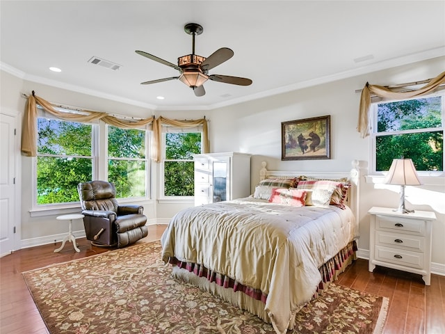 bedroom featuring ornamental molding, wood finished floors, visible vents, and baseboards