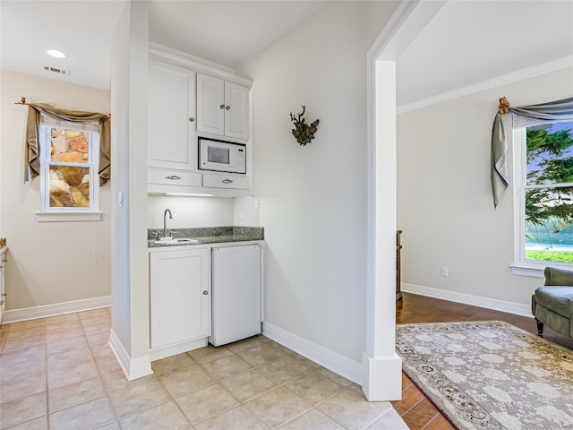 kitchen featuring white cabinetry, visible vents, baseboards, and white microwave