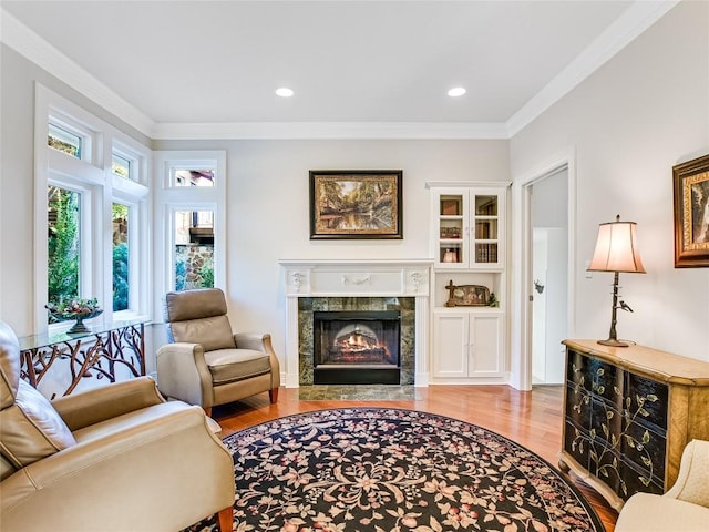 living room featuring recessed lighting, ornamental molding, wood finished floors, and a high end fireplace