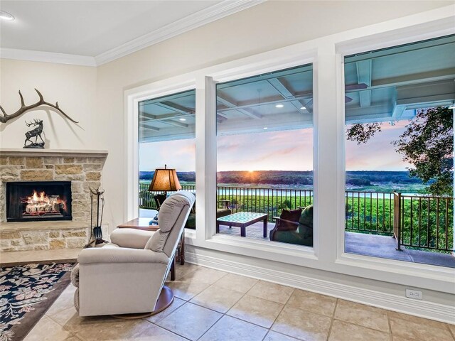 sitting room with a stone fireplace, ornamental molding, and light tile patterned flooring