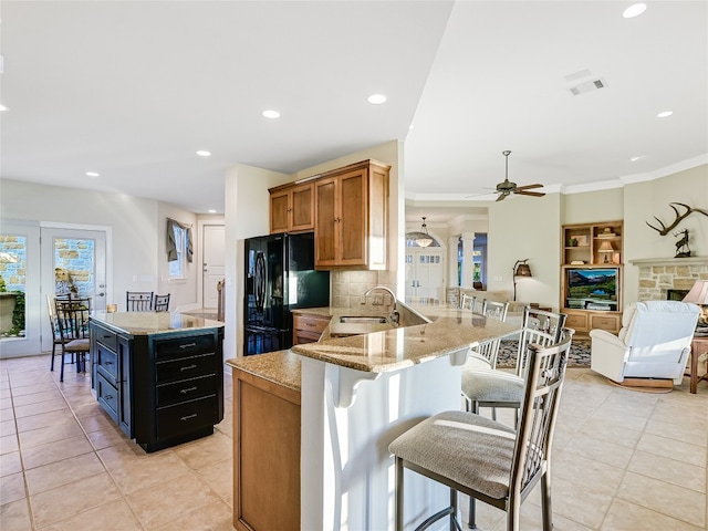 kitchen with a breakfast bar, brown cabinetry, freestanding refrigerator, open floor plan, and a peninsula