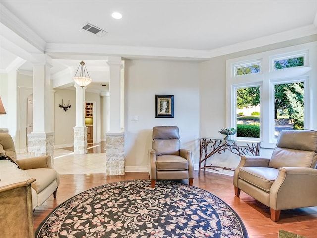 sitting room featuring visible vents, wood finished floors, and decorative columns