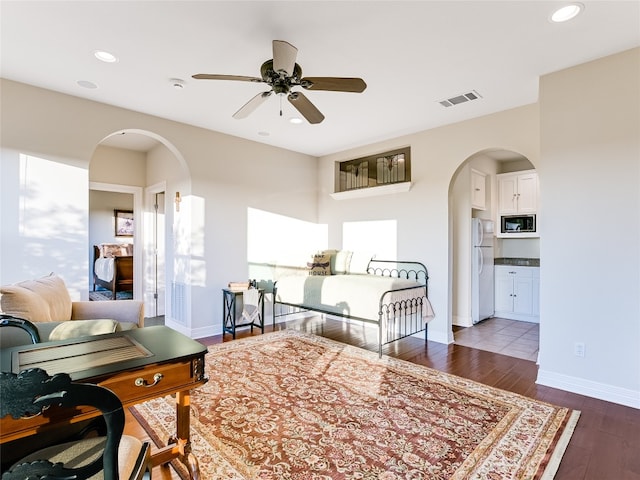 interior space with baseboards, visible vents, arched walkways, ceiling fan, and dark wood-type flooring