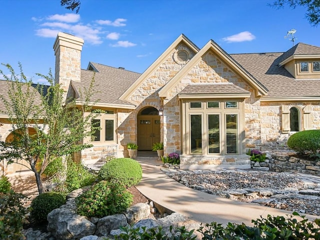 view of front of house with a shingled roof and a chimney