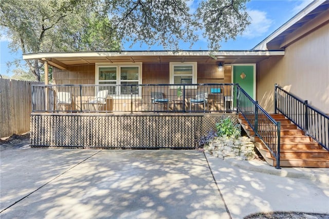 ranch-style home with covered porch, a patio area, fence, and stairs