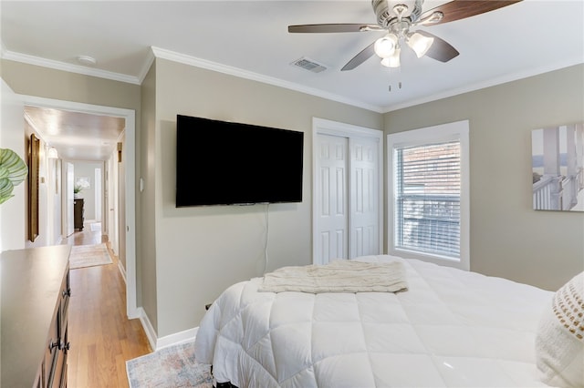 bedroom with light hardwood / wood-style floors, ornamental molding, a closet, and ceiling fan