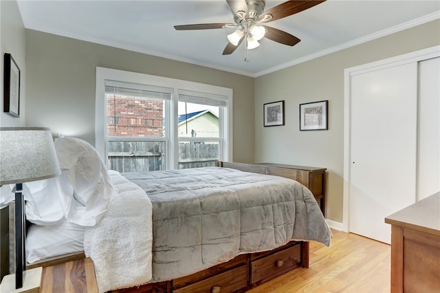 bedroom featuring ornamental molding, light hardwood / wood-style flooring, a closet, and ceiling fan