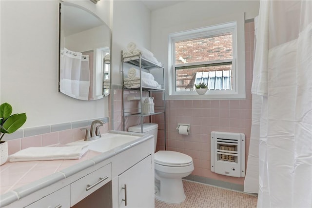 full bath featuring tile walls, heating unit, toilet, vanity, and tile patterned flooring