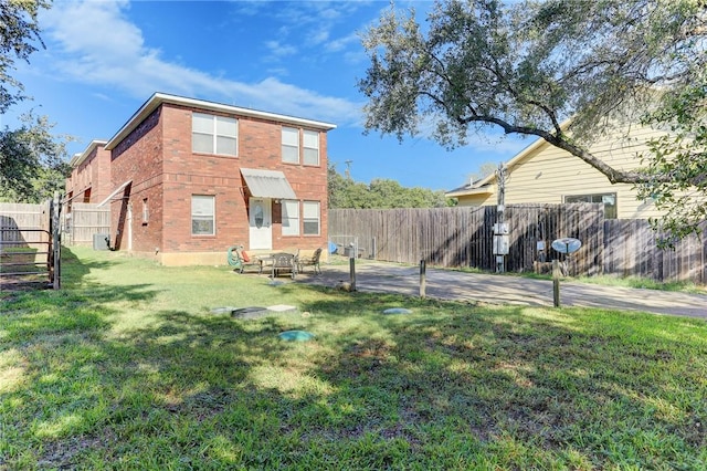 back of property with a patio area, a fenced backyard, brick siding, and a lawn