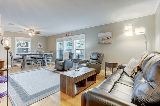 living room featuring ceiling fan, light wood finished floors, visible vents, and baseboards