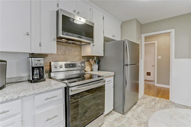 kitchen featuring white cabinets, tasteful backsplash, light stone counters, and stainless steel appliances