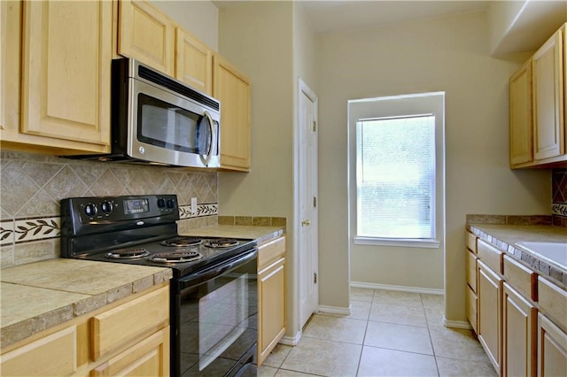 kitchen featuring black / electric stove, backsplash, a healthy amount of sunlight, and light tile patterned floors